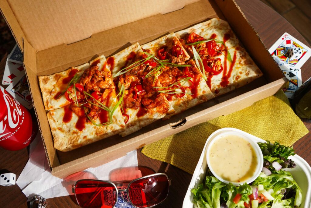 Image of hot chick flatbread with a can of coke and a salad